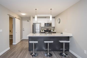 A modern kitchen with a bar stool in front of the island.